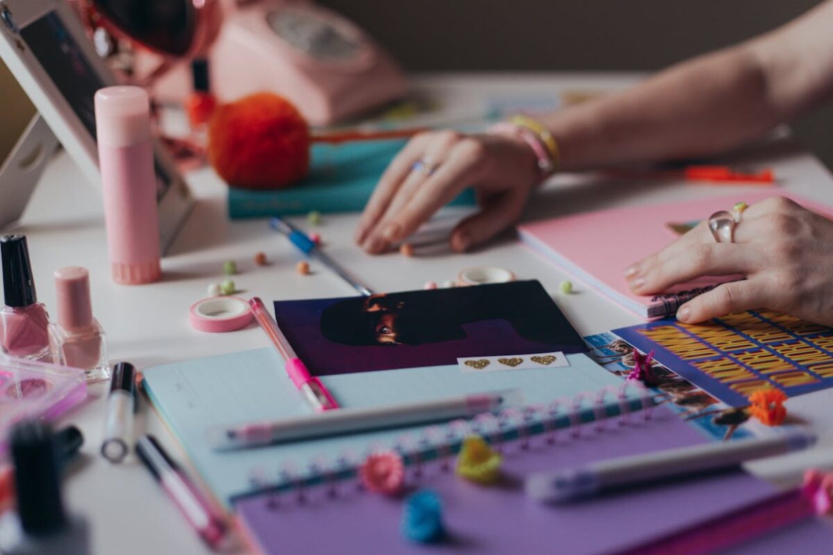 A close-up of a vibrant and colorful workspace featuring stationery and a woman's hands organizing supplies.